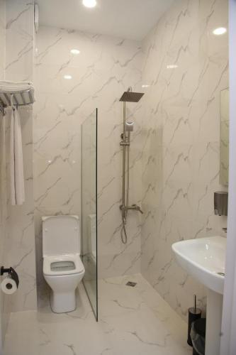 a white bathroom with a toilet and a sink at Mn Hotel Borjomi in Borjomi