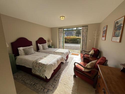 a bedroom with two beds and a chair and a window at Semeil Farm Holiday Lets in Strathdon