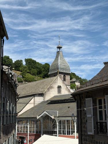 an old building with a tower with a cross on it at Murat - Le Duplex By Murat in Murat
