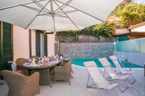 a patio with a table and chairs and an umbrella at Villa Lucia Laglio in Laglio