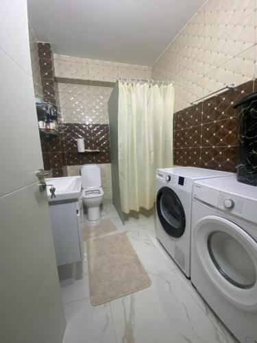 a bathroom with a washing machine and a toilet at AJ Apartments in Kosovo Polje