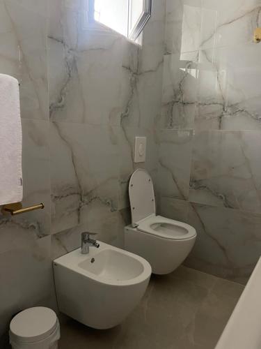 a white bathroom with a toilet and a sink at Durres Garden Stay in Durrës