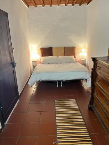 a bedroom with a bed with two lamps and a tiled floor at La Casetta di Guido in Pitigliano