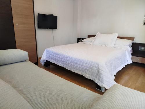 a bedroom with two beds and a flat screen tv at Pelivan Apartments in Kaštela