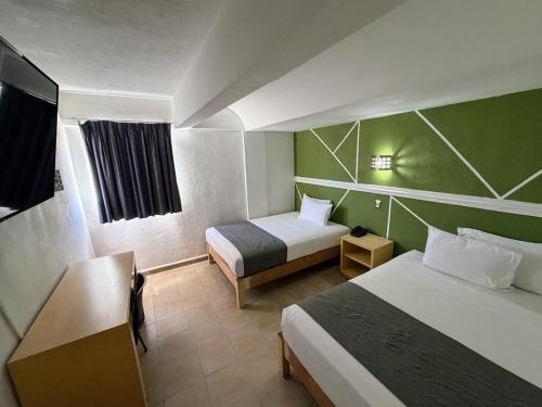 Ein Hotelzimmer mit zwei Betten und grünen Wänden in der Unterkunft Hotel Nueva Zelanda in León