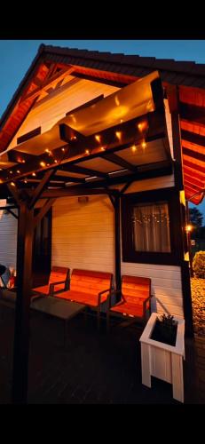 a patio with chairs and lights on a house at Białe Domki Mrzeżyno, wypoczynek w ciszy i zieleni in Mrzeżyno