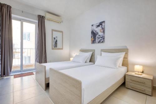 two beds in a room with a window at NEW - 2BR Beach side apt by SF HOMES in Sliema
