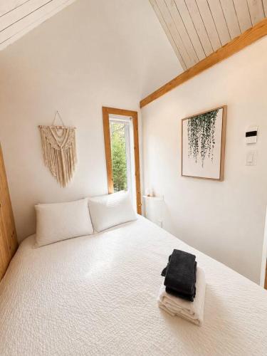 ein Schlafzimmer mit einem weißen Bett, auf dem eine schwarze Tasche liegt in der Unterkunft Nature Getaway with Lake, Horseback Riding & BBQ in Sainte-Marguerite