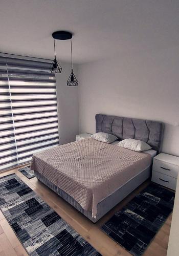 a bedroom with a bed and a large window at Apartman Eldin Panonika in Tuzla
