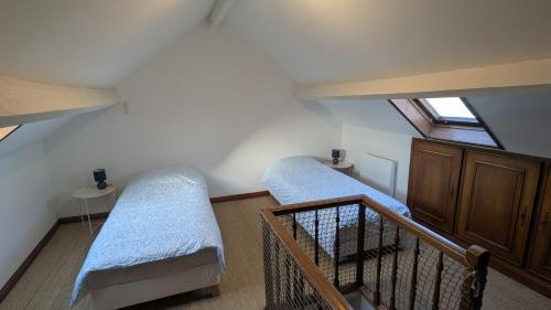 a attic room with two beds and a staircase at Le Cocon des Sables in Sangatte