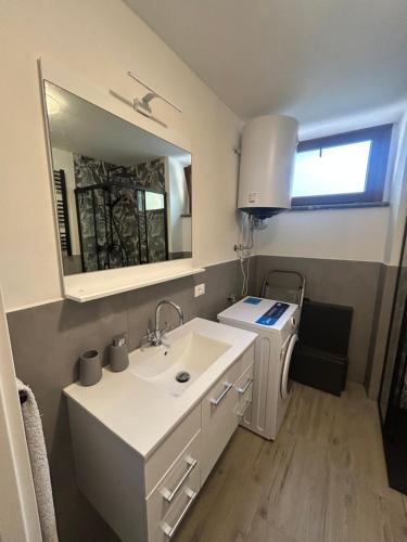 a white bathroom with a sink and a mirror at LA CASETTA di AURORA in Riomagno