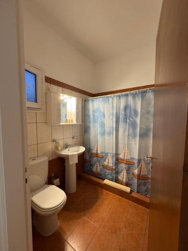 a bathroom with a toilet and a sink and a shower curtain at Dream catcher 1 in Agia Theodoti