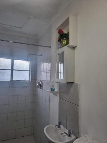 a white bathroom with a sink and a mirror at Green leaves in Mahikeng