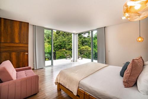 a bedroom with a large bed and a pink chair at Casa campestre en el Eje Cafetero in Circasia