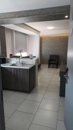 a kitchen with a sink and a table and a chair at Suites André Confort Ejecutivo in Aguascalientes