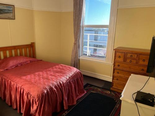 a bedroom with a bed and a dresser and a window at Sullivans backpackers in Waimate
