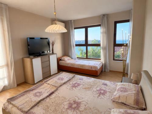 a bedroom with a bed and a tv and windows at Villa Bella Sozopol in Sozopol