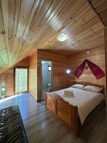 a bedroom with a large bed in a wooden room at Casa de Vacanta Cascada in Vidra