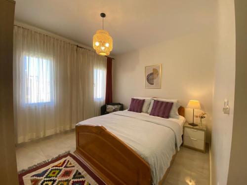 a bedroom with a large bed and a chandelier at Mountain View luxe chalet Ras elhikma families only in Ras Elhekma