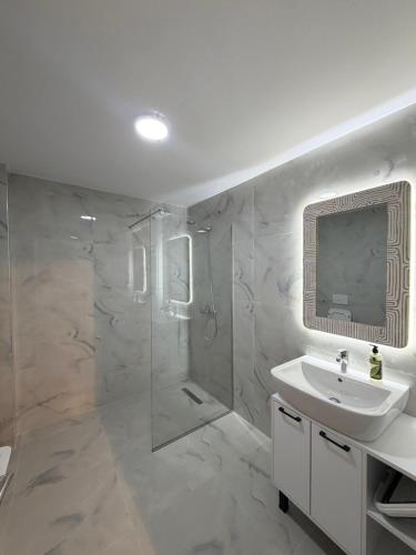 a white bathroom with a shower and a sink at D'stay by Dastid in Golem