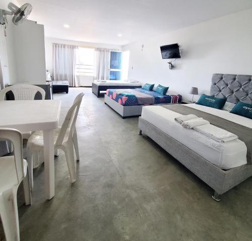 a living room with two beds and a table at Hostel HM Caribe in Santa Marta