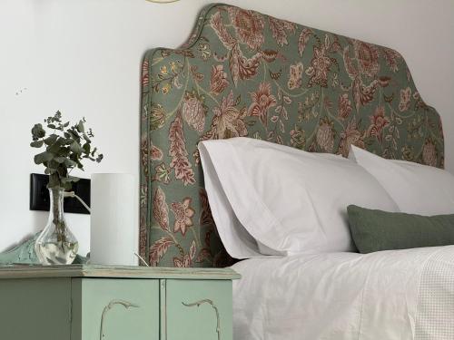 a bed with a headboard and a vase of flowers on a table at Apartamento Casa Nela 3 in Medellín