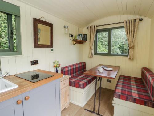 a small kitchen with two benches and a table at The Three Spaniels Shepherds Hut in Llanybyther