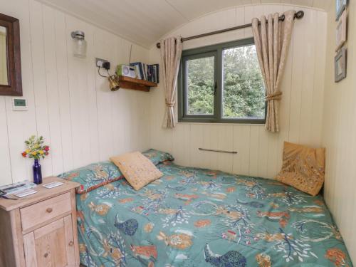 a small bedroom with a bed and a window at The Three Spaniels Shepherds Hut in Llanybyther