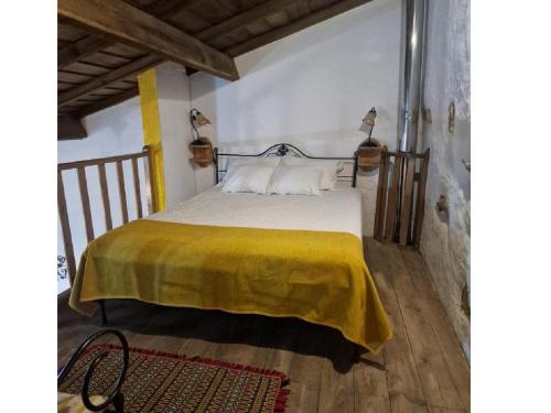 a bedroom with a bed with a yellow blanket on it at Encosta do Castelo in Portel