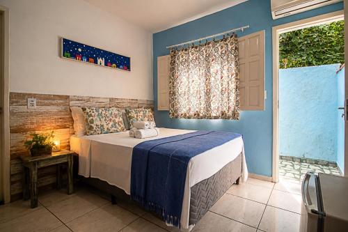 a bedroom with a bed with blue walls and a window at Pousada Universo Arraial in Arraial d'Ajuda