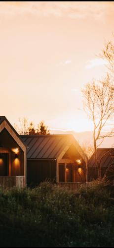 a house with the sun setting behind it at Golden Circle Cabins in Laugarvatn