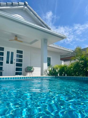 a swimming pool in front of a house at Samui Serenity 63 Pool Villa in Choeng Mon Beach