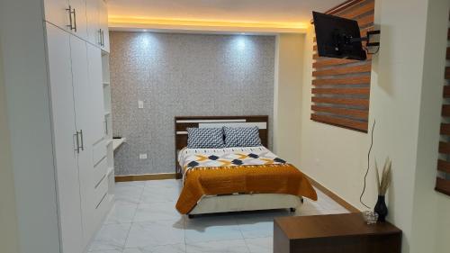 a bedroom with a bed and a tv on a wall at Hospedaje Smart Wasi Sucre in Sucre