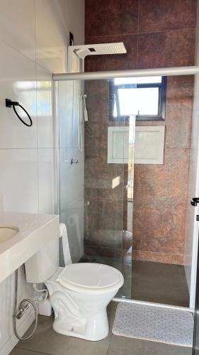 a bathroom with a toilet and a glass shower at Casa de Chame Refúgio da Serra in Brasília