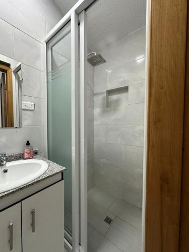 a white bathroom with a shower and a sink at Amazing Home - Habitación Triple in Baños