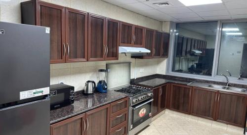 a kitchen with wooden cabinets and a stove top oven at Ajman Beach Apartments in Ajman 