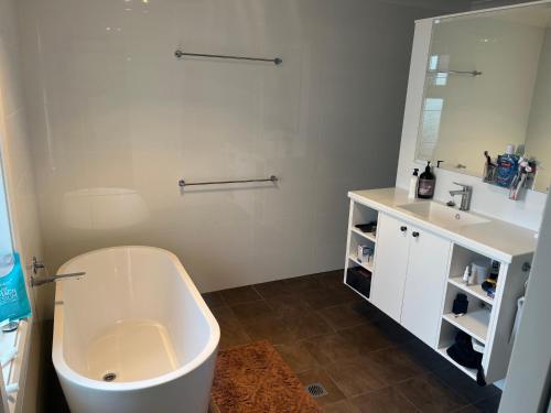 a bathroom with a tub and a sink and a mirror at Armidale Central Guest House in Armidale