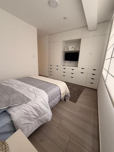 a white bedroom with a bed and a television at Punta Hermosa Apartment in Punta Hermosa