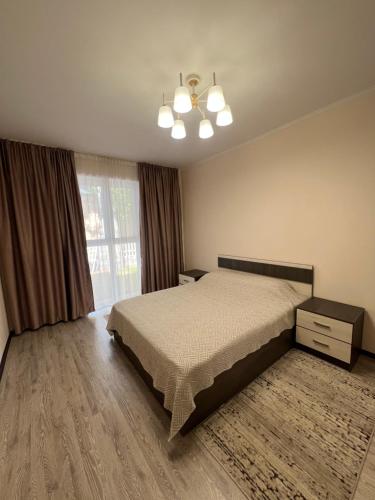 a bedroom with a bed and a large window at РадугаВест58а in Koshkolʼ