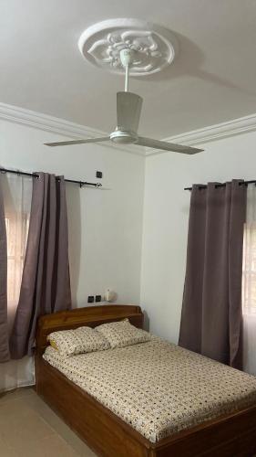 a bedroom with a bed with a ceiling fan at New ACROPOLE APPART in Komé