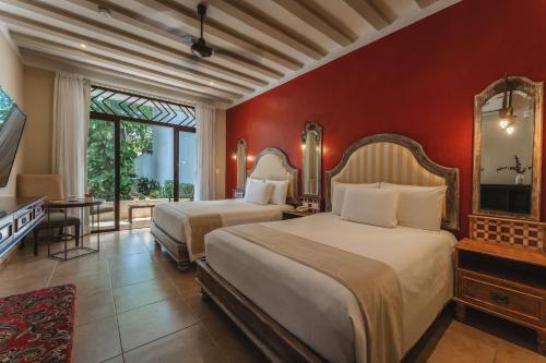 a bedroom with two beds and a flat screen tv at Casa Zafiro Hotel - Adults Only, Mérida in Mérida