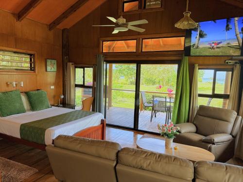 a bedroom with a bed and a living room at Sigasiga Sands Boutique Bungalows in Savusavu