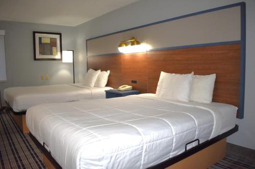 a hotel room with two beds with white sheets at AmericInn by Wyndham Frankfort IN in Frankfort