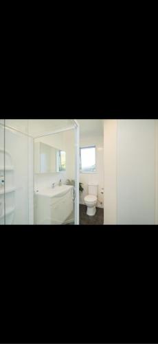 a bathroom with a white tub and a toilet at Otatara Bush Haven in Otatara
