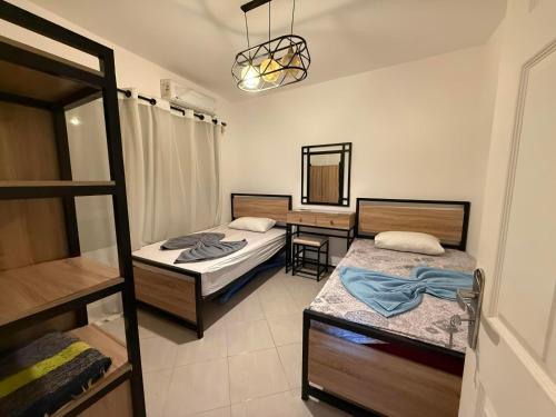 ein Schlafzimmer mit zwei Betten und einem Schreibtisch mit Spiegel in der Unterkunft Lagoon Blumar Hotel Chalet in Ain Suchna