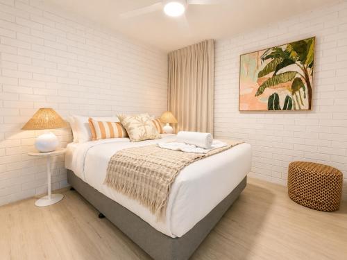a white bedroom with a large bed and a lamp at Alex Headland Unit Views to the Ocean in Alexandra Headland