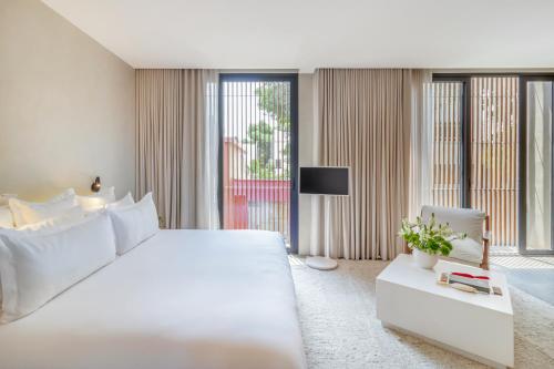 a white bedroom with a large bed and a tv at Octavia Casa in Mexico City