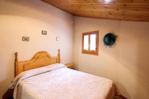 1 dormitorio con 1 cama con cabecero de madera y ventana en Cal Puxica, en Gósol