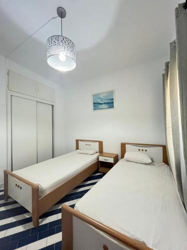 a room with two beds and a chandelier at Marina Escape, 2BD, Pool and Beach in Hammam Sousse