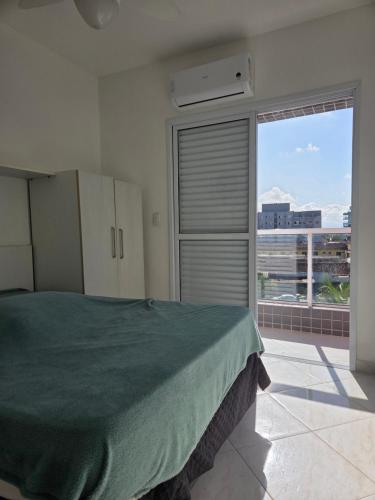 a bedroom with a bed and a large window at terraços do maitinga in Bertioga